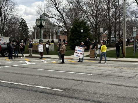 Opposition groups stand across the street from the restaurant. (Bob Rich)